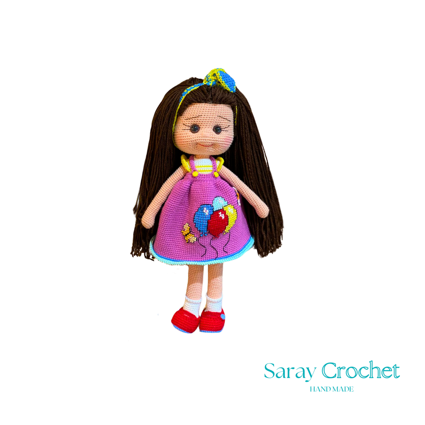 Handmade doll with long brown hair, wearing a purple dress with balloon print and red shoes, with a blue bow in her hair.