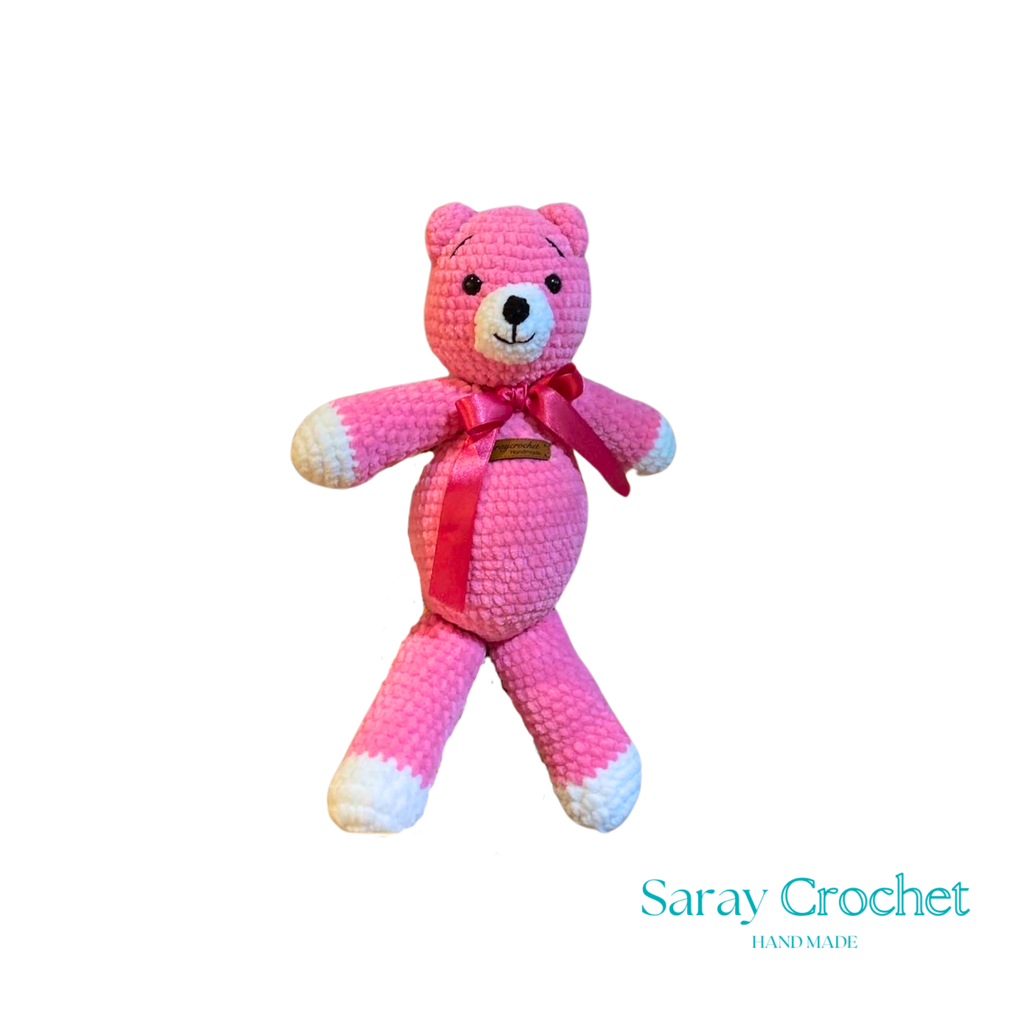 Pink crochet teddy bear with a bow tie on a white background, branded 'Saray Crochet'.