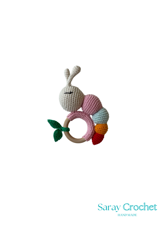 Crocheted caterpillar rattle toy with wooden ring on a white background, branded 'Saray Crochet'.