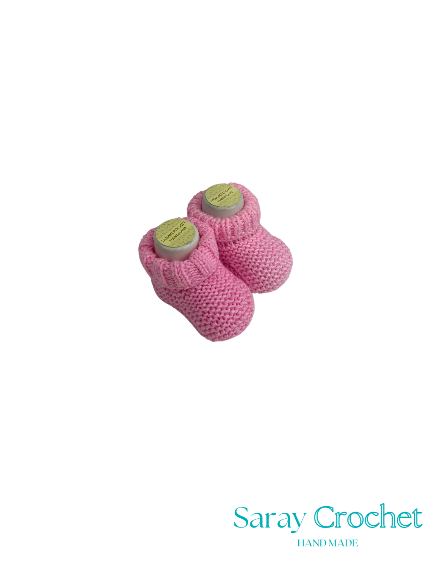 Pair of pink knitted baby booties with green buttons on a white background, branded 'Saray Crochet'.