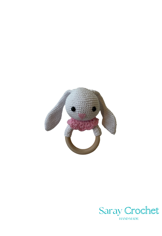Crocheted bunny rattle with wooden ring on a white background, branded 'Saray Crochet'.