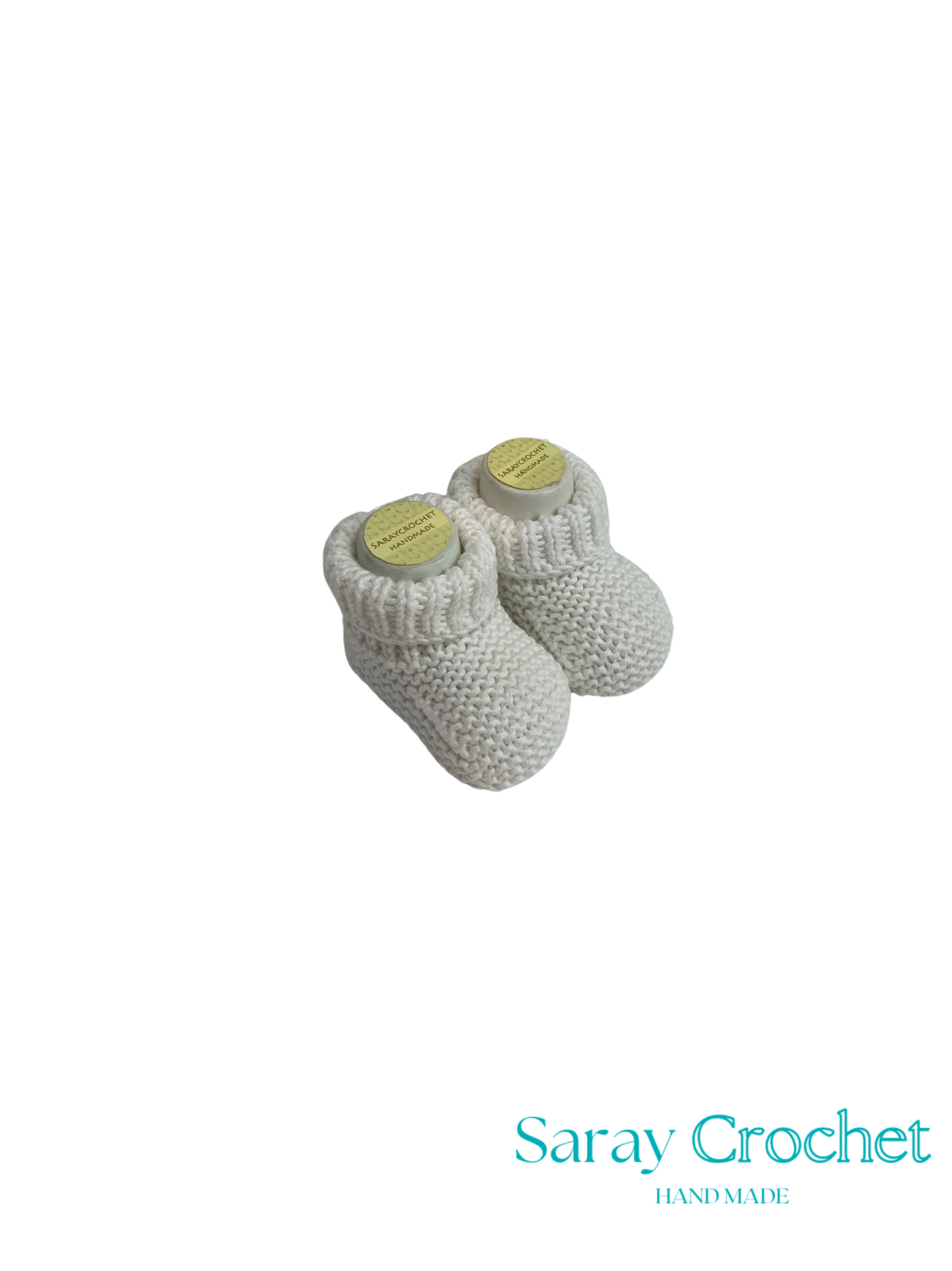 Pair of white knitted baby booties with yellow accents on a white background, branded 'Saray Crochet'.