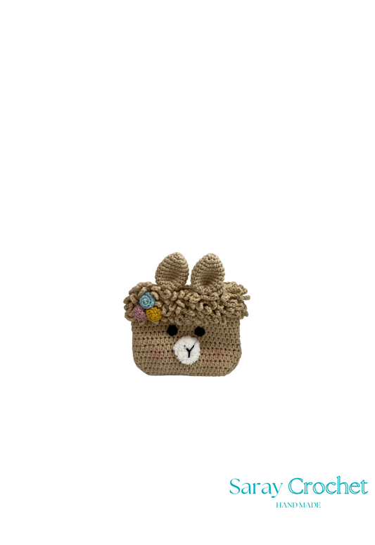 Crocheted bear head with floral decorations on a white background, branded 'Saray Crochet'.