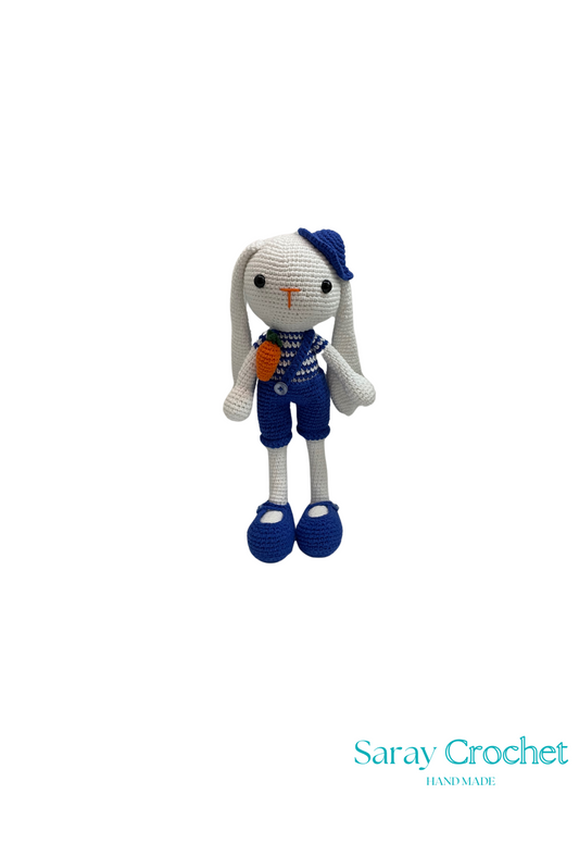 Crocheted toy rabbit in blue outfit with 'Saray Crochet' branding.