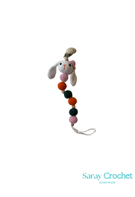 Crocheted bunny with colorful pom-poms on a white background, branded 'Saray Crochet'.