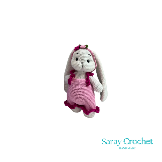 Crocheted bunny toy with pink dress on white background