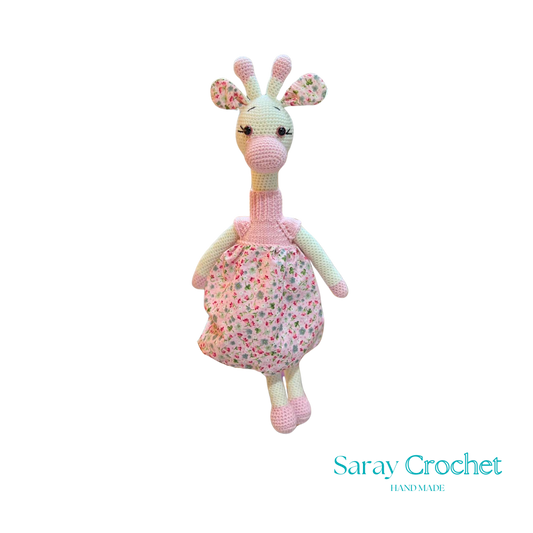 Handmade plush giraffe toy with a pink floral dress and white accents, part of the SarayCrochet collection.