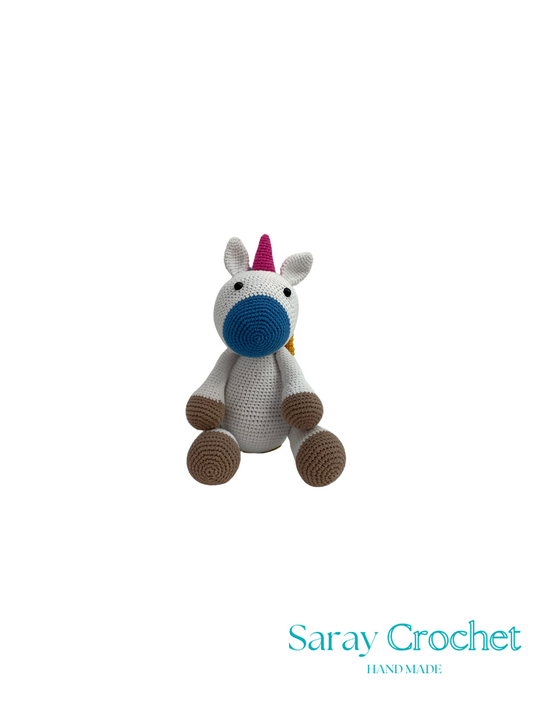 Crocheted unicorn toy with a pink horn on a white background, branded 'Saray Crochet'.