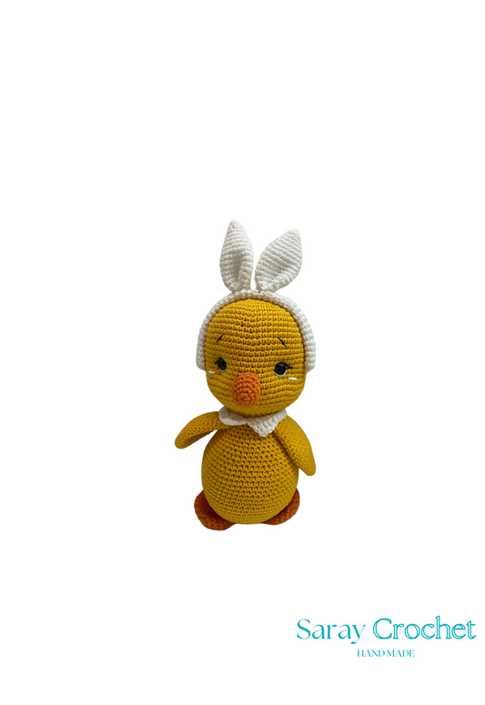 A handcrafted plush toy resembling a chicken with a white collar and a small white hat, made from 100% cotton, against a plain background with the watermark 'Saray Crochet'.