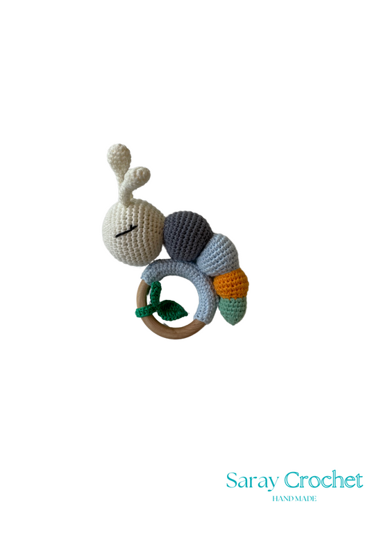 A colorful crochet caterpillar toy with a wooden ring attached to its back.