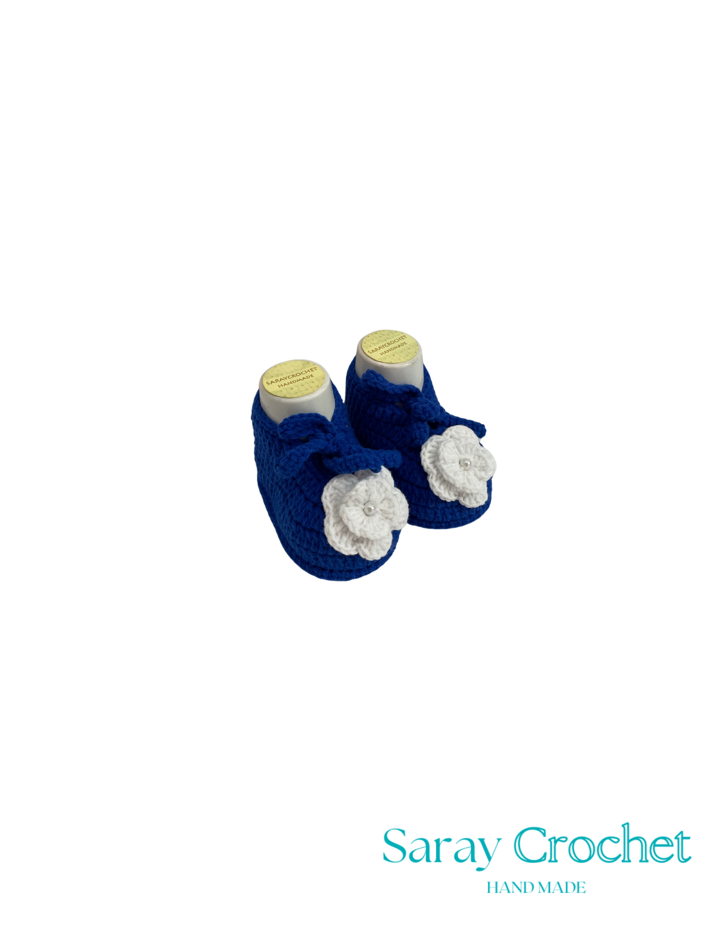 Pair of blue baby booties with white flowers on a white background, branded 'Saray Crochet'.
