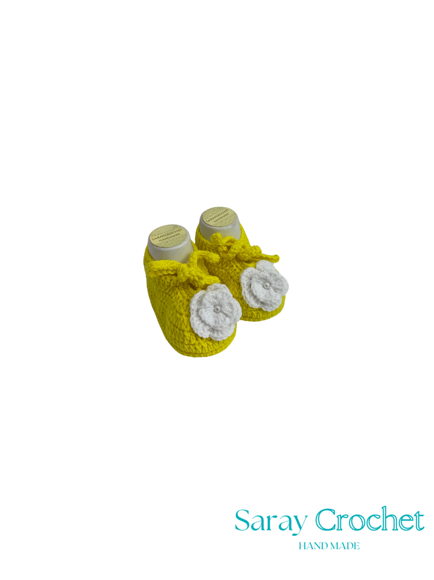 Pair of yellow and white baby booties with 'Saray Crochet' branding on a white background.