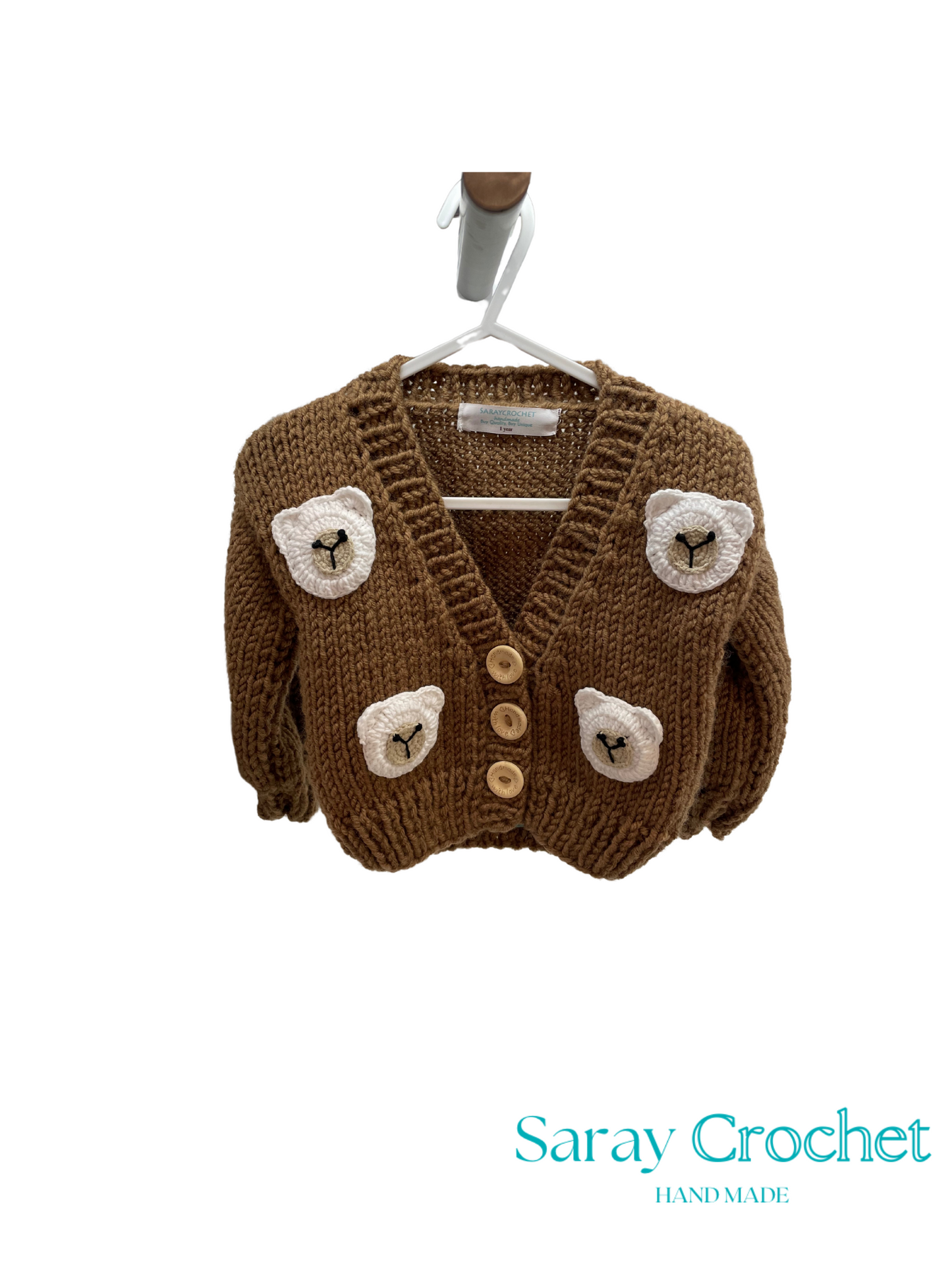 Brown knitted cardigan with bear face designs on a hanger, branded 'Saray Crochet'.