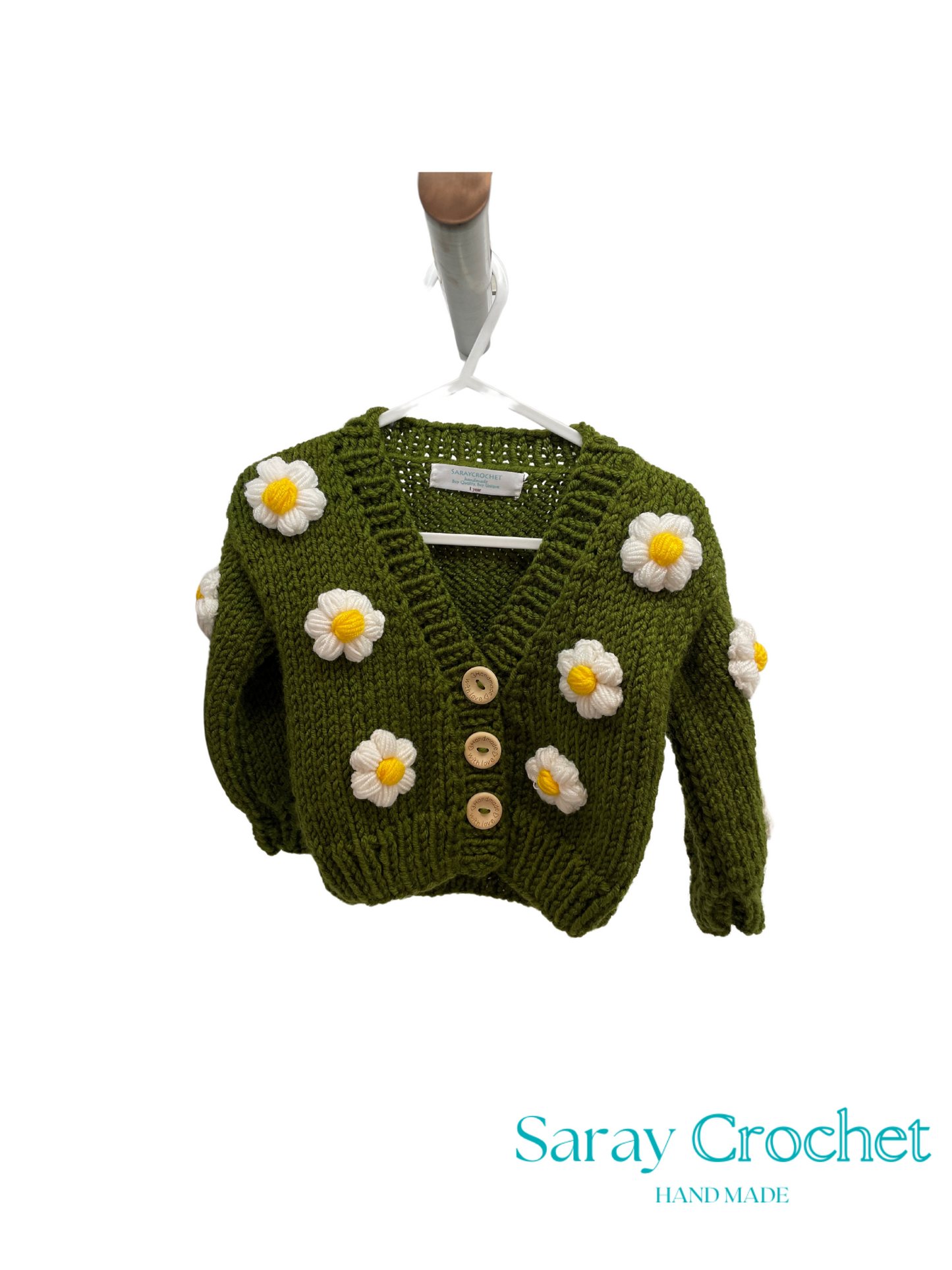 Green knitted cardigan with flower decorations on a white background, branded 'Saray Crochet'.