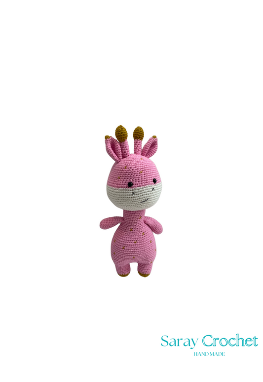 Handmade plush giraffe toy with pink and beige colors, featuring a smiling face and small horns, on a white background with the watermark 'Saray Crochet'.