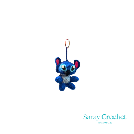 A blue character keychain with a design resembling a stitch from a fabric or crochet pattern.