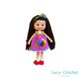 Handmade doll with long brown hair, wearing a purple dress with balloon print and red shoes, with a blue bow in her hair.