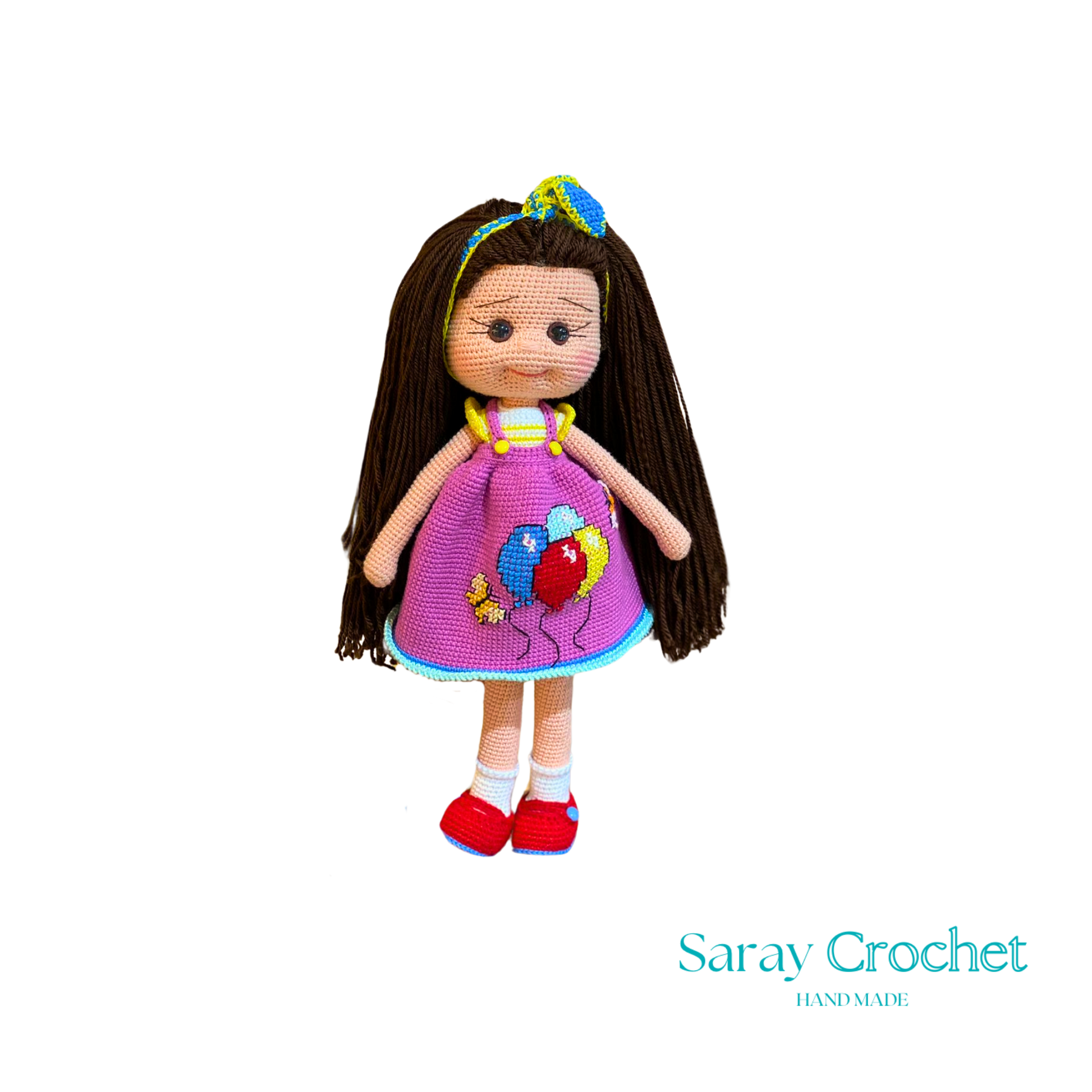 Handmade doll with long brown hair, wearing a purple dress with balloon print and red shoes, with a blue bow in her hair.
