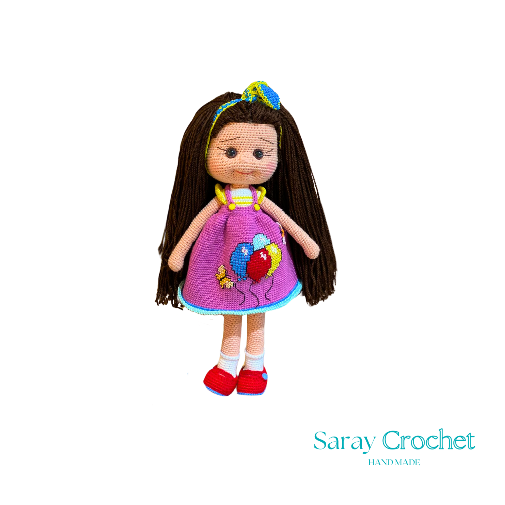 Handmade doll with long brown hair, wearing a purple dress with balloon print and red shoes, with a blue bow in her hair.