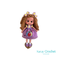 Handmade doll with curly brown hair and a purple dress with balloon print, complete with a bow and lace details.