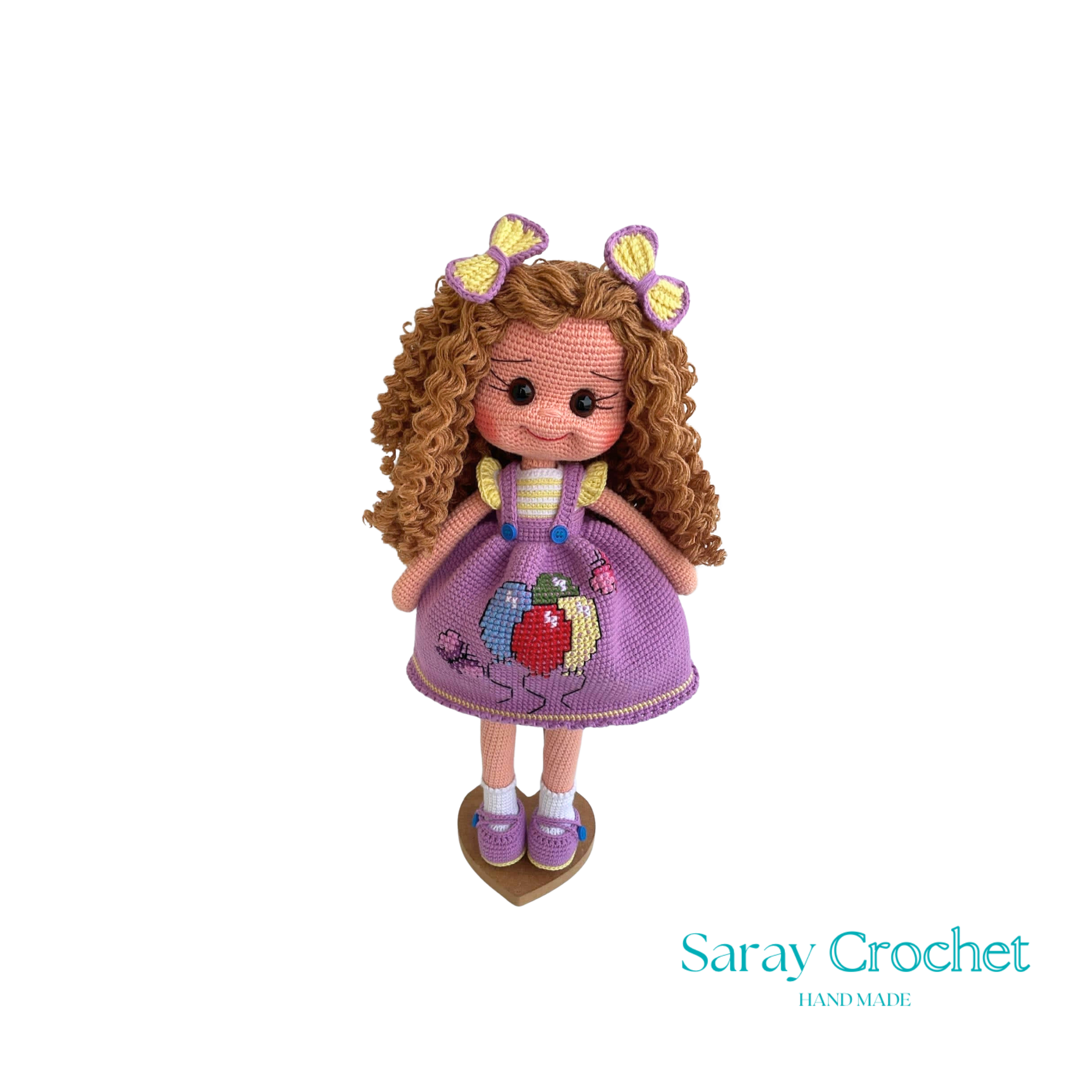 Handmade doll with curly brown hair and a purple dress with balloon print, complete with a bow and lace details.