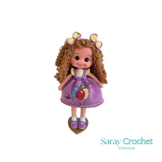 Handmade doll with curly brown hair and a purple dress with balloon print, complete with a bow and lace details.