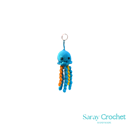Crocheted octopus keychain with blue body and orange tentacles on a white background, branded 'Saray Crochet'.