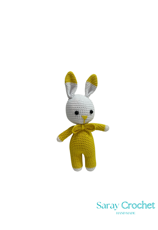 A handcrafted plush toy rabbit with a yellow body and white face, ears, and feet, named Sofi, made by SarayCrochet.