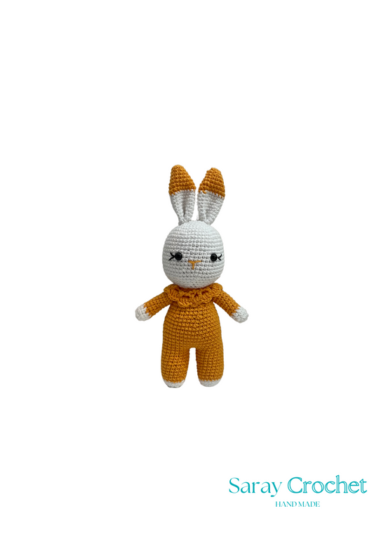 Crocheted bunny toy in mustard yellow outfit on white background