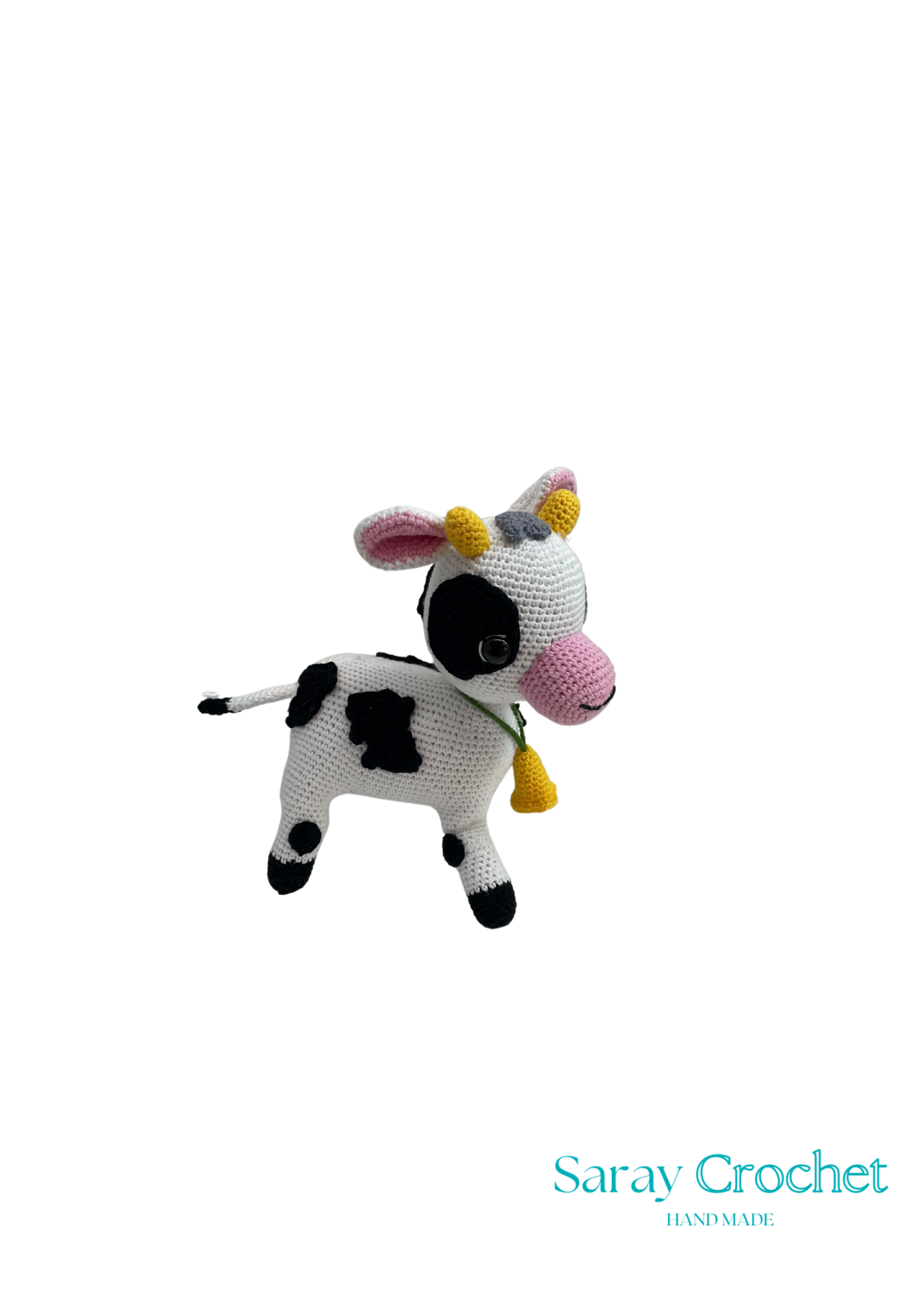 A crochet stuffed toy depicting a black and white cow with yellow horns and a pink nose.