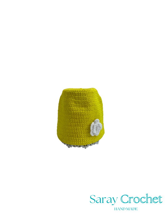 Yellow crocheted skirt with a white flower on a white background, branded 'Saray Crochet'.