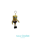 Crocheted keychain in the shape of a character with 'Saray Crochet' branding.