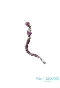 A silicone teething bead teether for a baby carrier, with purple and pink beads and a metal clip.