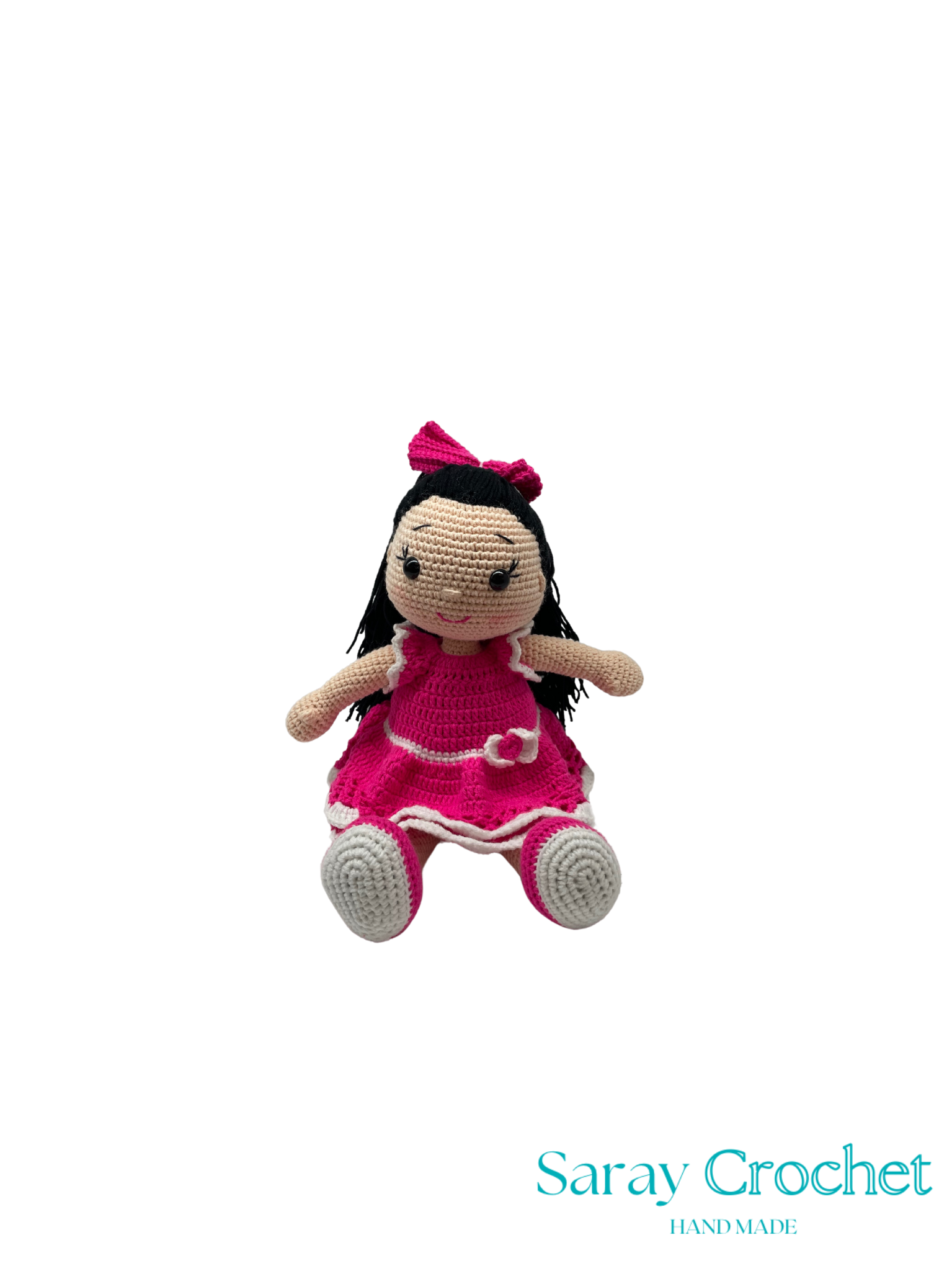 Handmade crochet doll in a pink dress with a bow on a white background, branded 'Saray Crochet'.