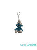 Crocheted blue bear keychain with a white hat on a white background, branded 'Saray Crochet'.