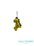 Crocheted dinosaur keychain on a white background with 'Saray Crochet' branding.