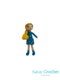 Crocheted doll with blue dress and yellow hair on a white background, branded 'Saray Crochet'.