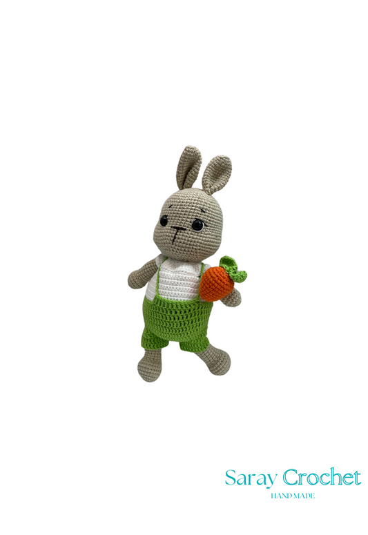 Handmade crochet toy resembling a rabbit with green overalls and a carrot, crafted from cotton.