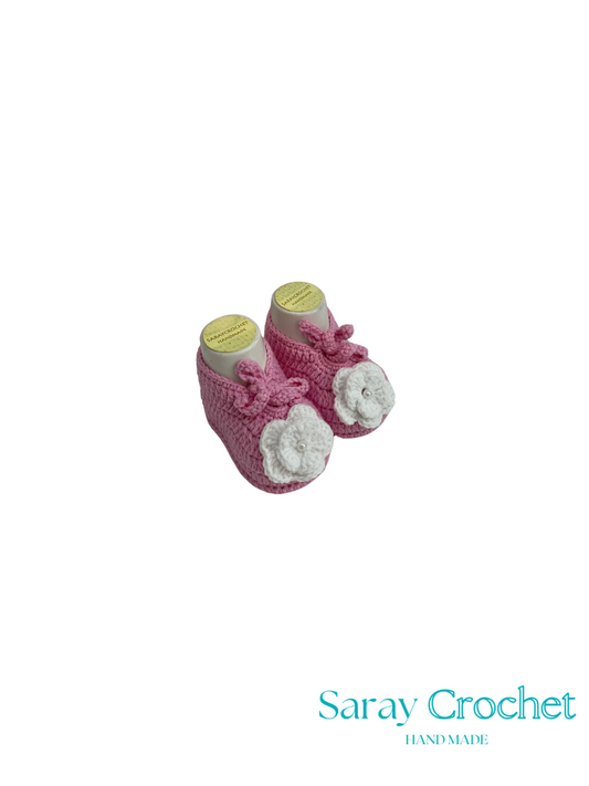 Pink baby booties with white flowers on a white background, branded 'Saray Crochet'.