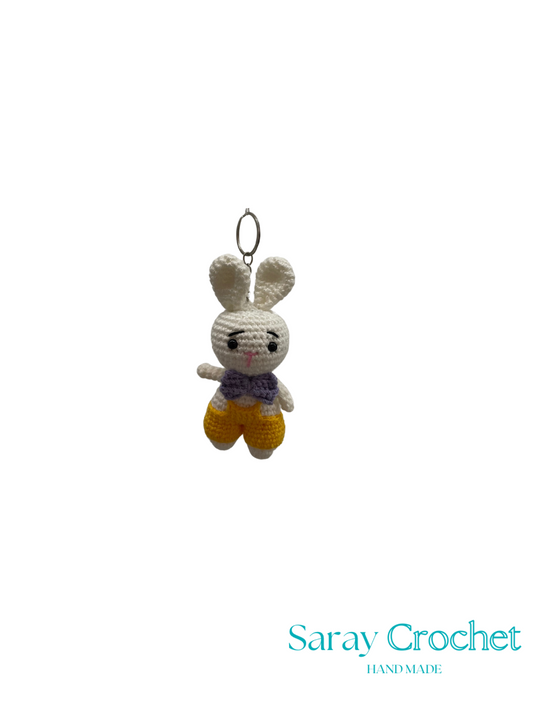 Crocheted bunny keychain with a purple scarf on a white background, branded 'Saray Crochet'.
