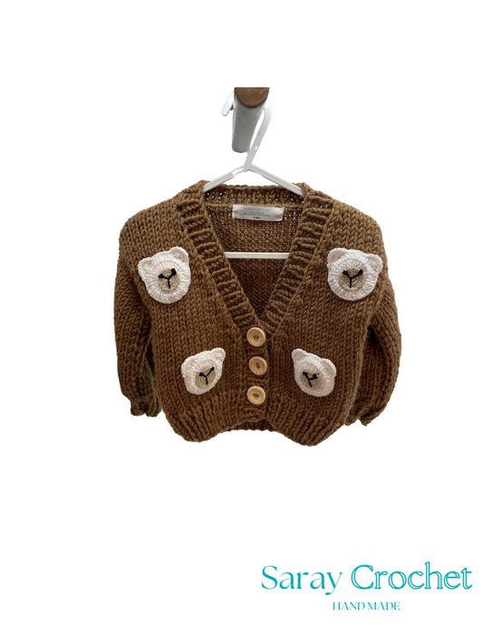 Brown knitted cardigan with bear face designs on a hanger, branded 'Saray Crochet'.