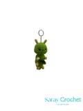 Green crocheted dragon keychain on a white background with 'Saray Crochet' branding.