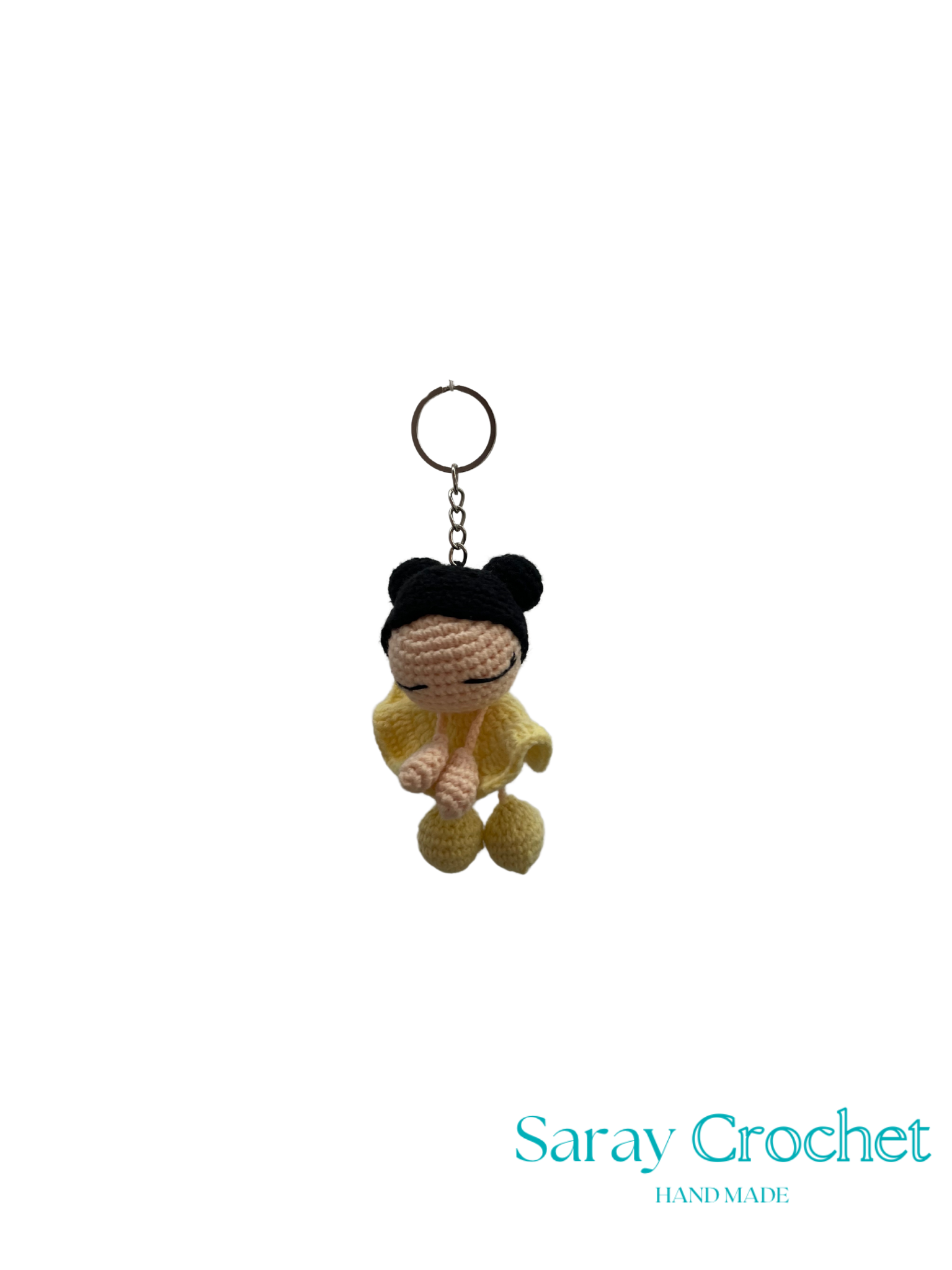 Crocheted keychain with a character wearing a yellow outfit on a white background, branded 'Saray Crochet'.