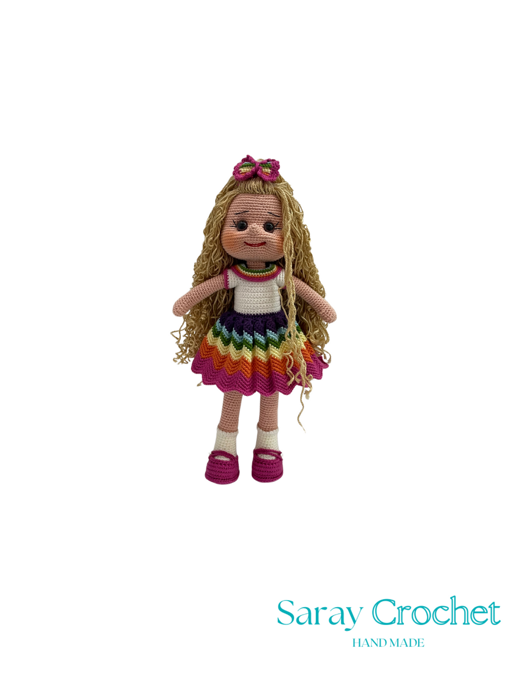 Knitted doll with colorful dress and hairband on a white background, branded 'Saray Crochet'.