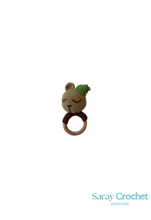 A crochet toy resembling a bear with a green detail on its head, made by Saray Crochet.