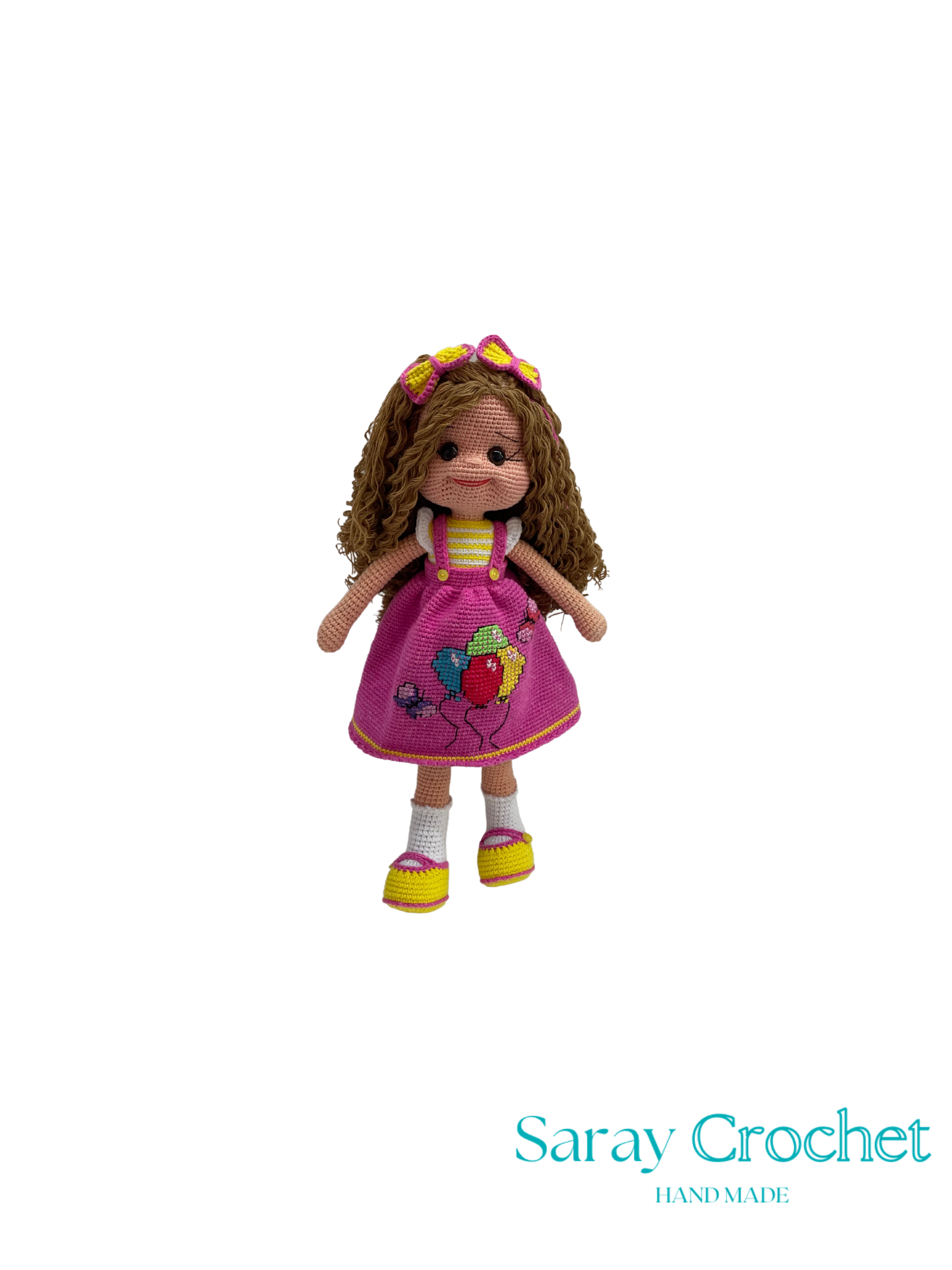 Crocheted doll with a pink dress and colorful shoes on a white background, branded 'Saray Crochet'.