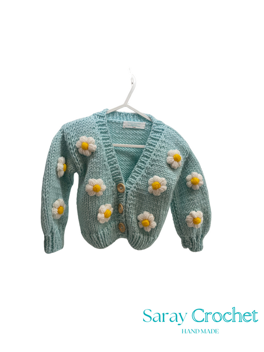 Knitted cardigan with flower decorations on a hanger, branded 'Saray Crochet'.