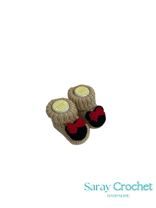 Pair of knitted baby booties with red bows on a white background, branded 'Saray Crochet'.