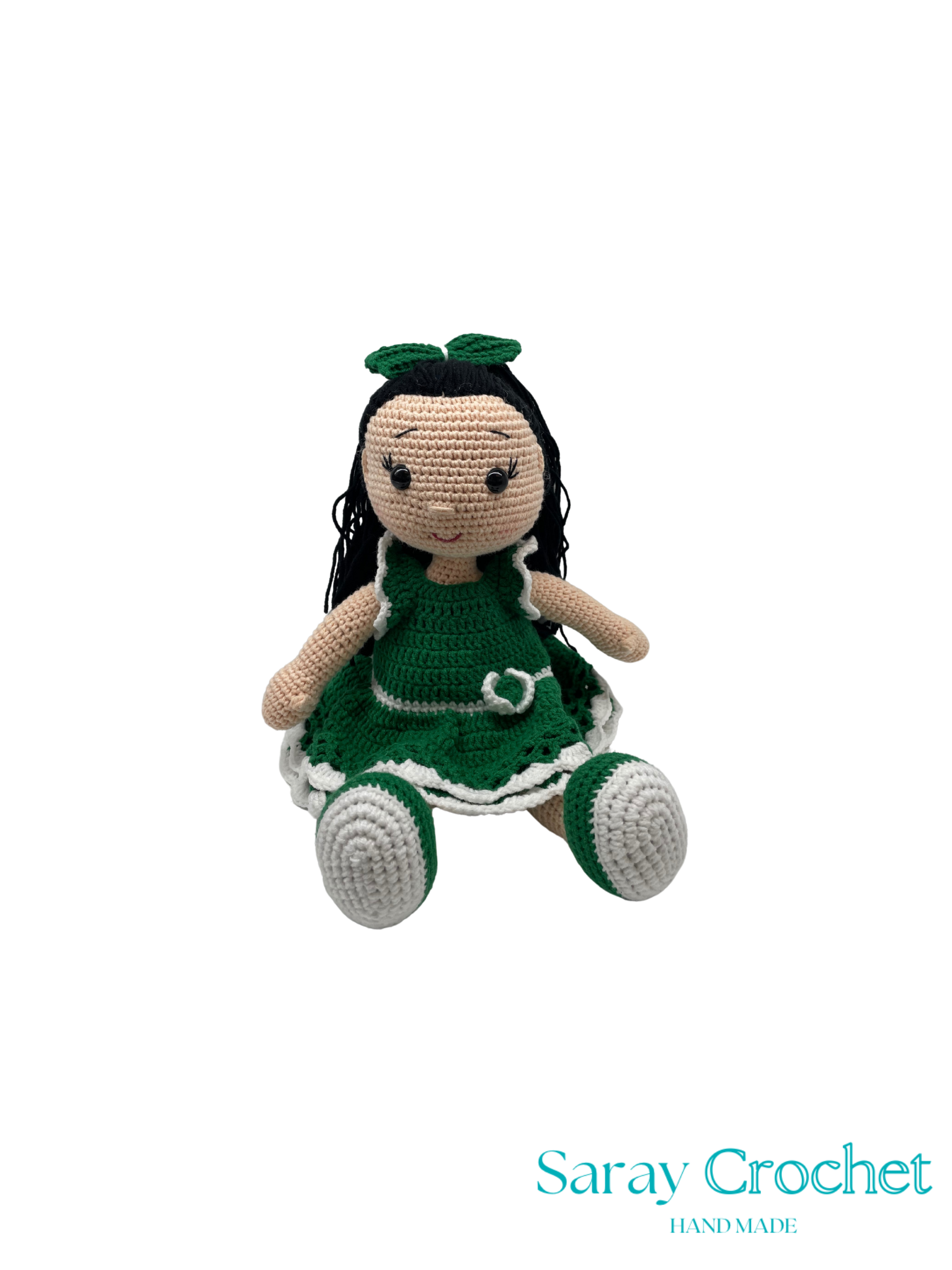 Crocheted doll in a green dress with a white background, featuring the brand 'Saray Crochet'.