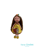 Handmade doll with a yellow dress featuring a forest animal motif, a carrot-themed apron, and a fluffy hairstyle, standing against a white background with the watermark 'Saray Crochet'.